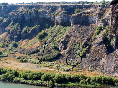 [Parchutist is circled in the photo and is about 30 feet above the canyon floor. An arrow points to a target on the ground. The target is several concentric circles spray-painted on the ground.]